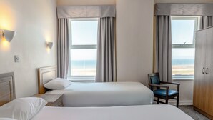 A hotel room with two beds, a chair, a wardrobe, and two windows with curtains. - Norbreck Castle Hotel Blackpool (Blackpool)