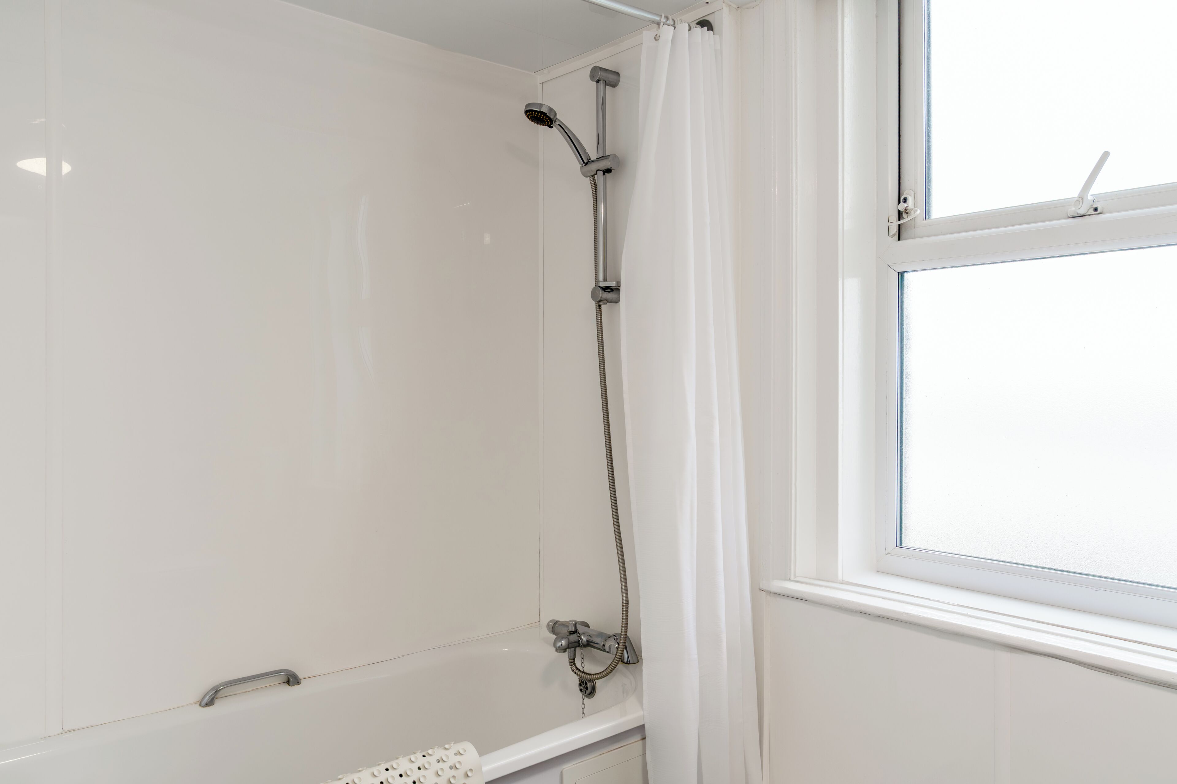Un baño con ducha, bañera y ventana.