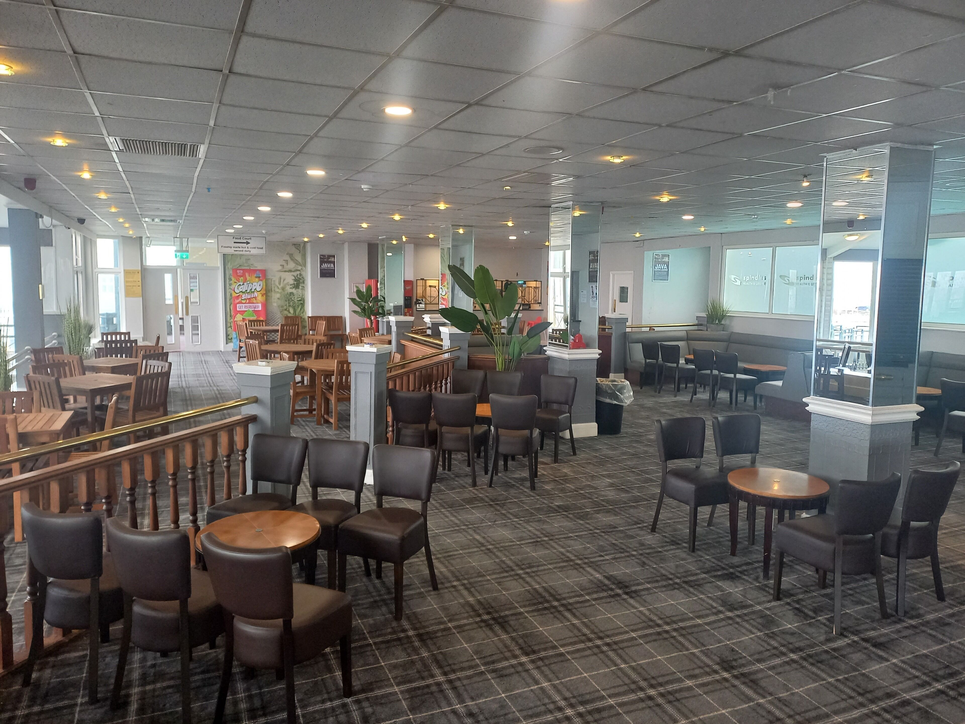 A spacious indoor area with multiple seating arrangements, including tables and chairs, and a central column structure.
