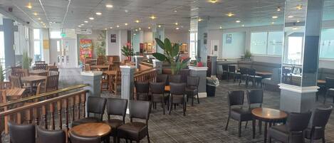 A spacious indoor area with multiple seating arrangements, including tables and chairs, and a central column structure.