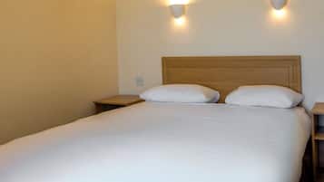 A neatly made bed with a wooden headboard, two bedside tables, and wall-mounted lighting.