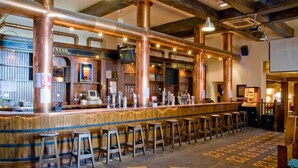 A bar area with copper pipes, wooden bar stools, and a counter with taps. - Norbreck Castle Hotel Blackpool (Blackpool)