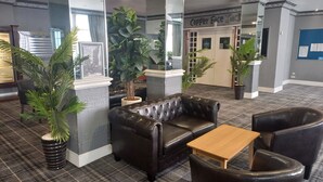 A lobby with a leather sofa, a wooden table, and potted plants. - Norbreck Castle Hotel Blackpool (Blackpool)