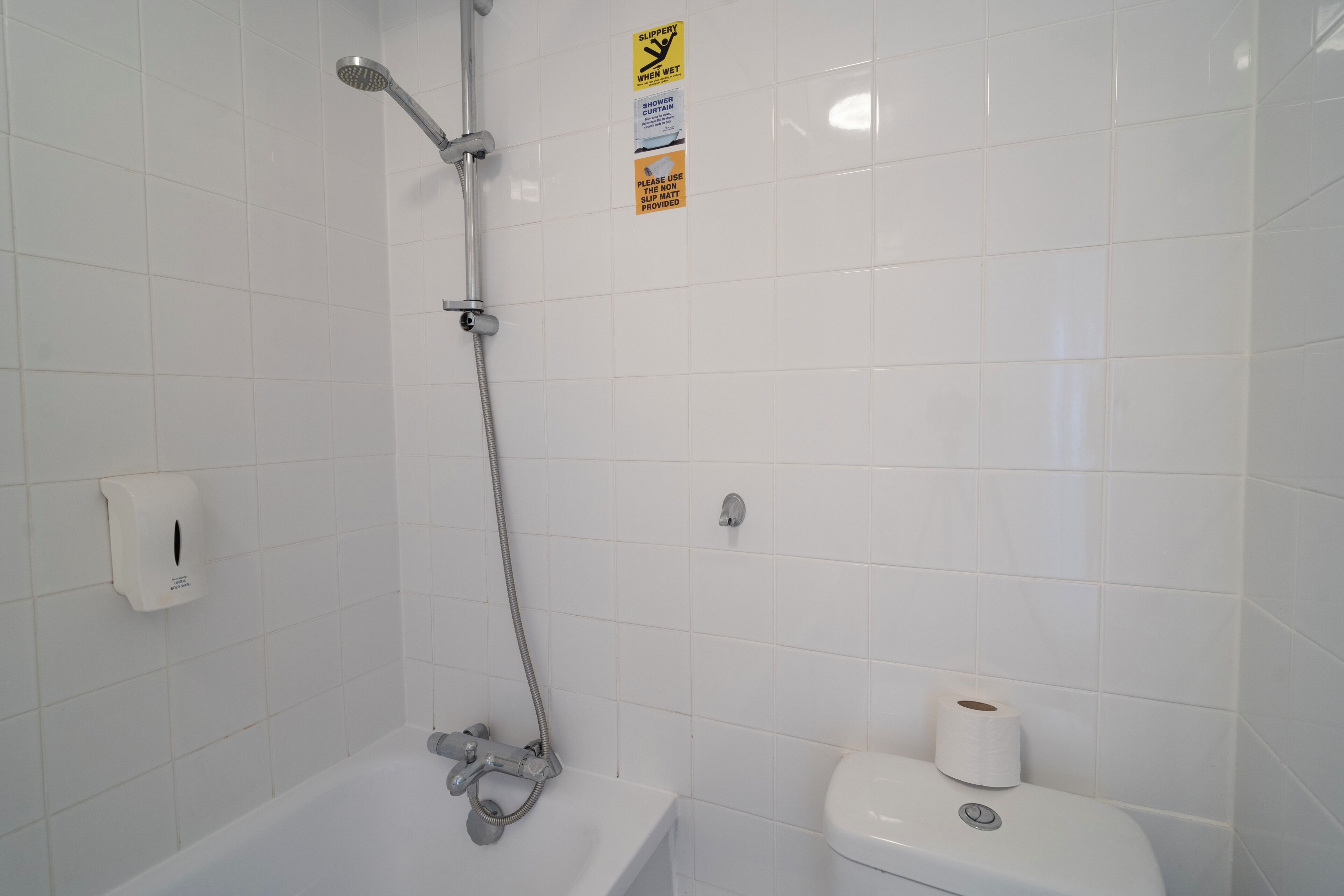 Ein Badezimmer mit Dusche, Toilette und einer Seifenspender.