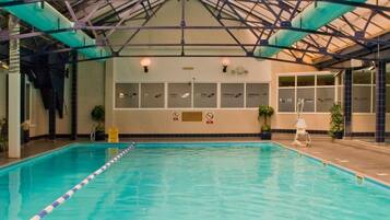 Swimmers can enjoy the pool surrounded by lush greenery and natural light.