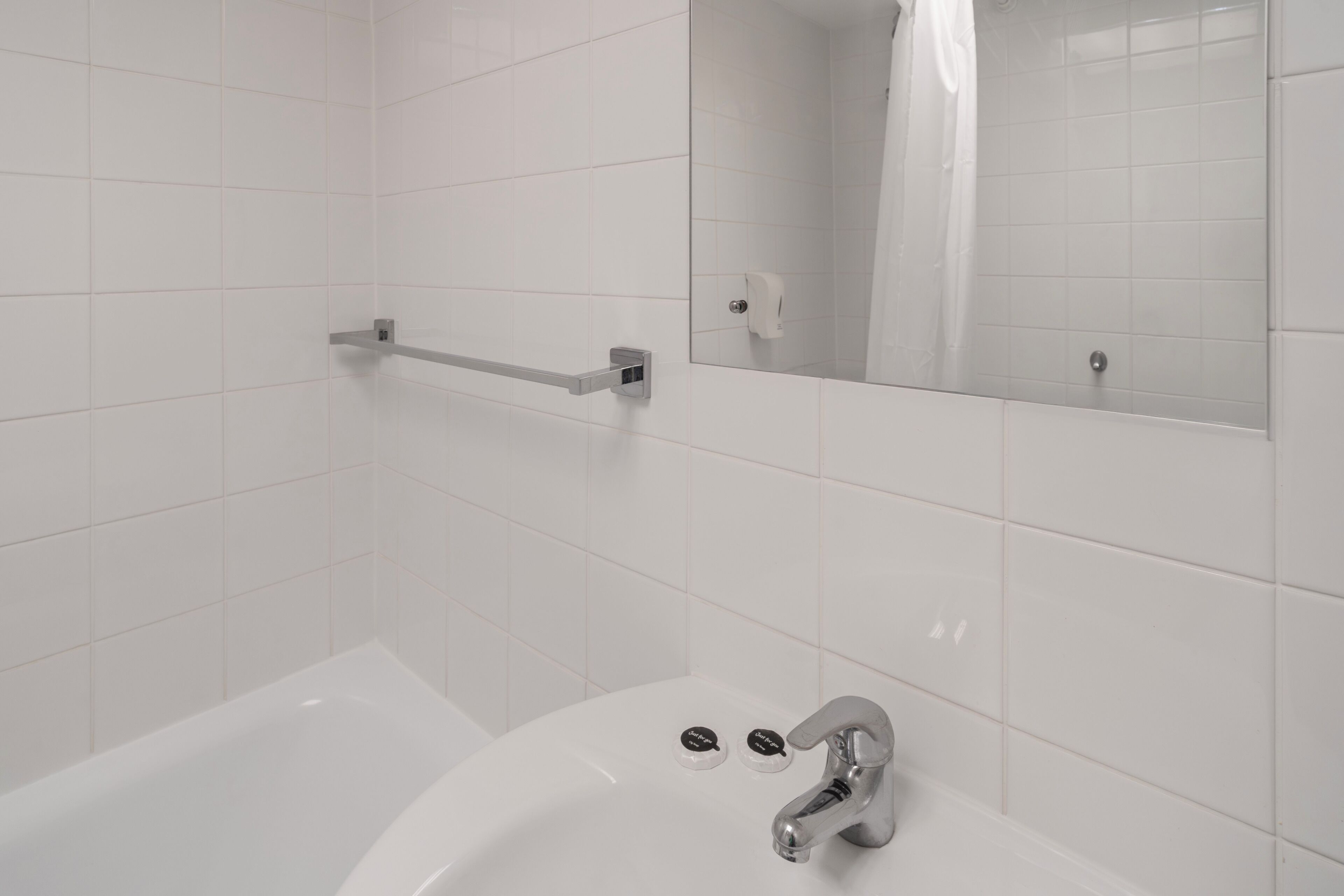 A bathroom with a white bathtub, a sink with a faucet, and a mirror above the sink.