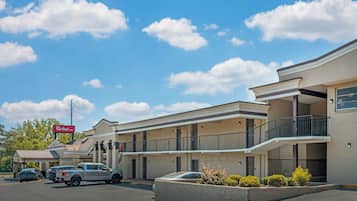 Un motel con una estructura de dos pisos, un área de estacionamiento techada y un letrero que indica el nombre 'Red Roof Inn'.