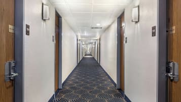 Un pasillo de hotel con alfombra estampada, puertas numeradas 109 y 110, y un letrero de 'Bienvenido' en cada puerta.
