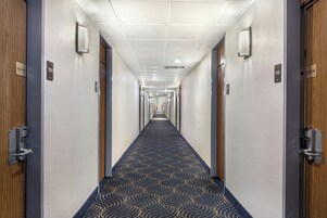 Un pasillo de hotel con alfombra estampada, puertas numeradas 109 y 110, y un letrero de 'Bienvenido' en cada puerta.