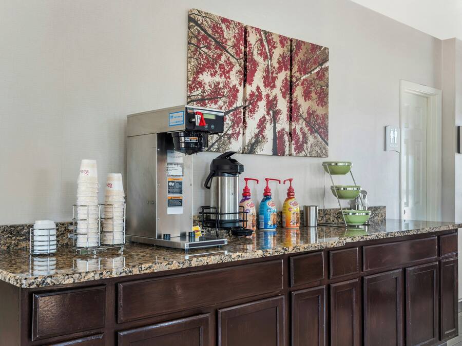 En køkkenbordplade med kaffemaskine, stablede kopper og krydderier.
