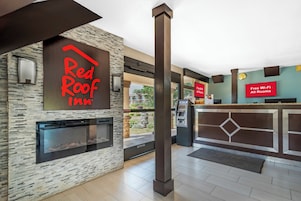 Zona de recepción de Red Roof Inn con pared de piedra, chimenea, cajero automático y un cartel que indica Wi-Fi gratuito en todas las habitaciones.