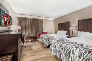 Ein Hotelzimmer mit Bett, Schreibtisch, Stuhl und Fernseher an der Wand.