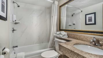 A bathroom with a bathtub, toilet, sink, and a large mirror.