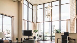 A spacious office with large windows, a chandelier, and modern furniture.