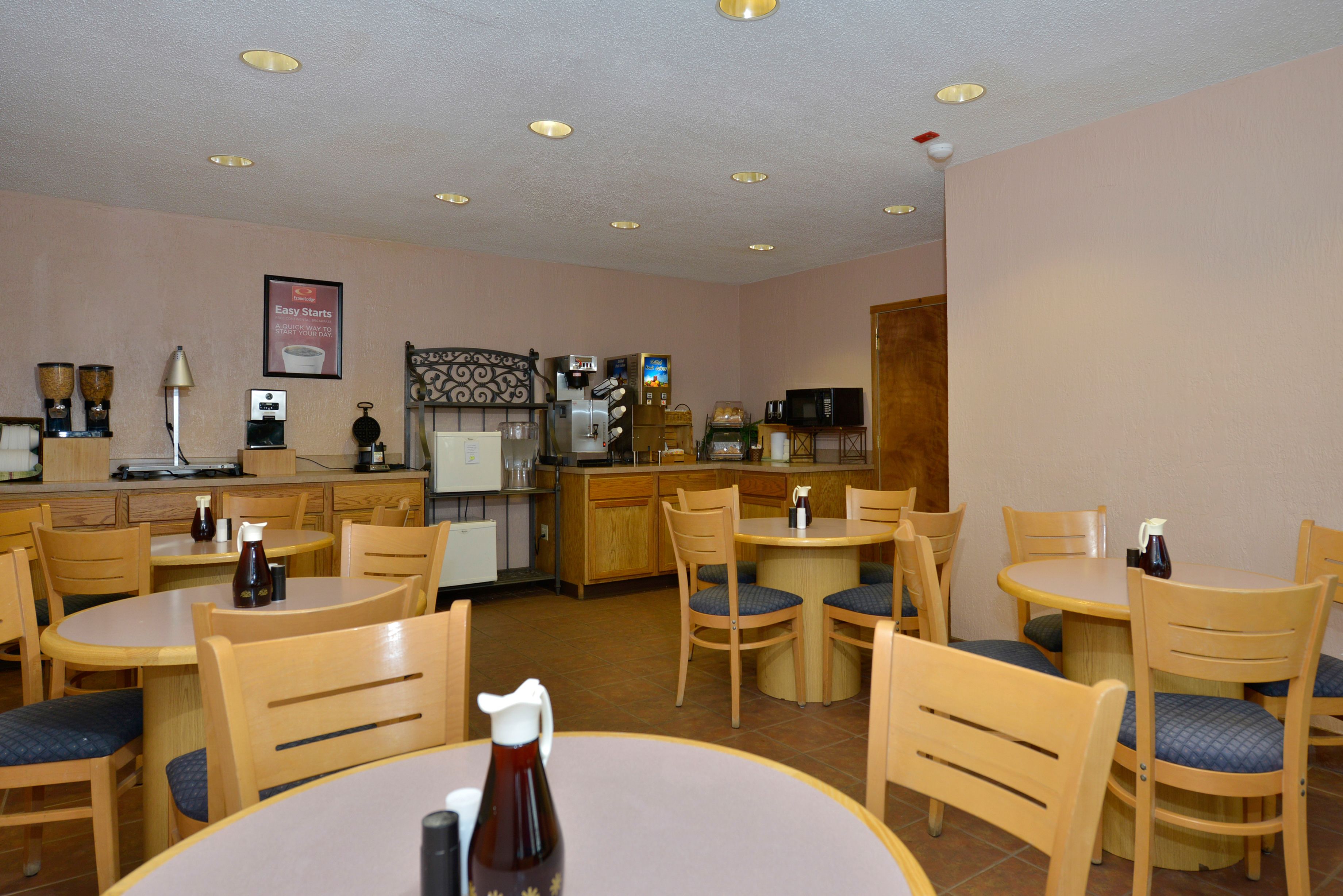 A restaurant with wooden tables and chairs, a coffee machine, and a microwave.
