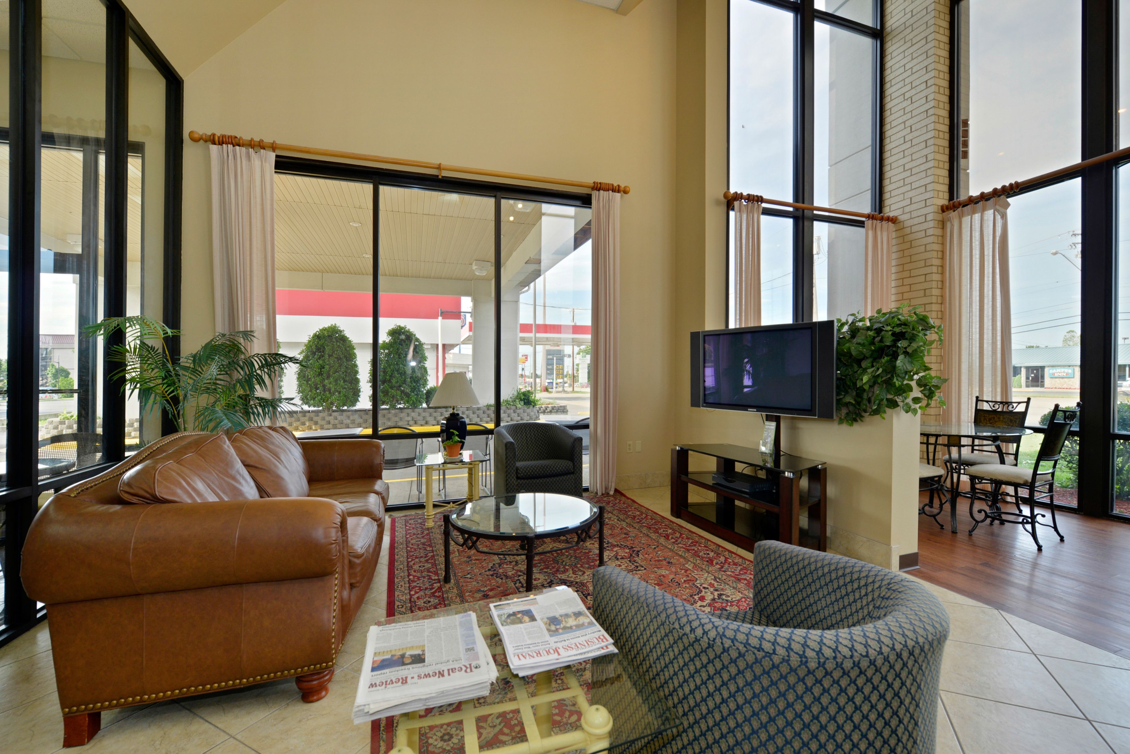 A spacious living area with a leather sofa, patterned armchair, and a flat-screen TV.