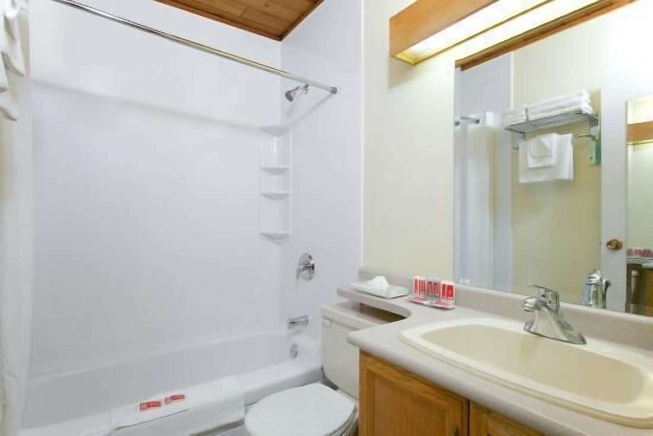 A bathroom with a bathtub, toilet, sink, and mirror.