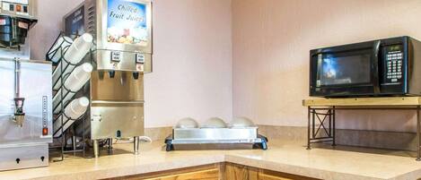 Una kitchenette equipada con cafetera, microondas y dispensador de zumo de frutas.