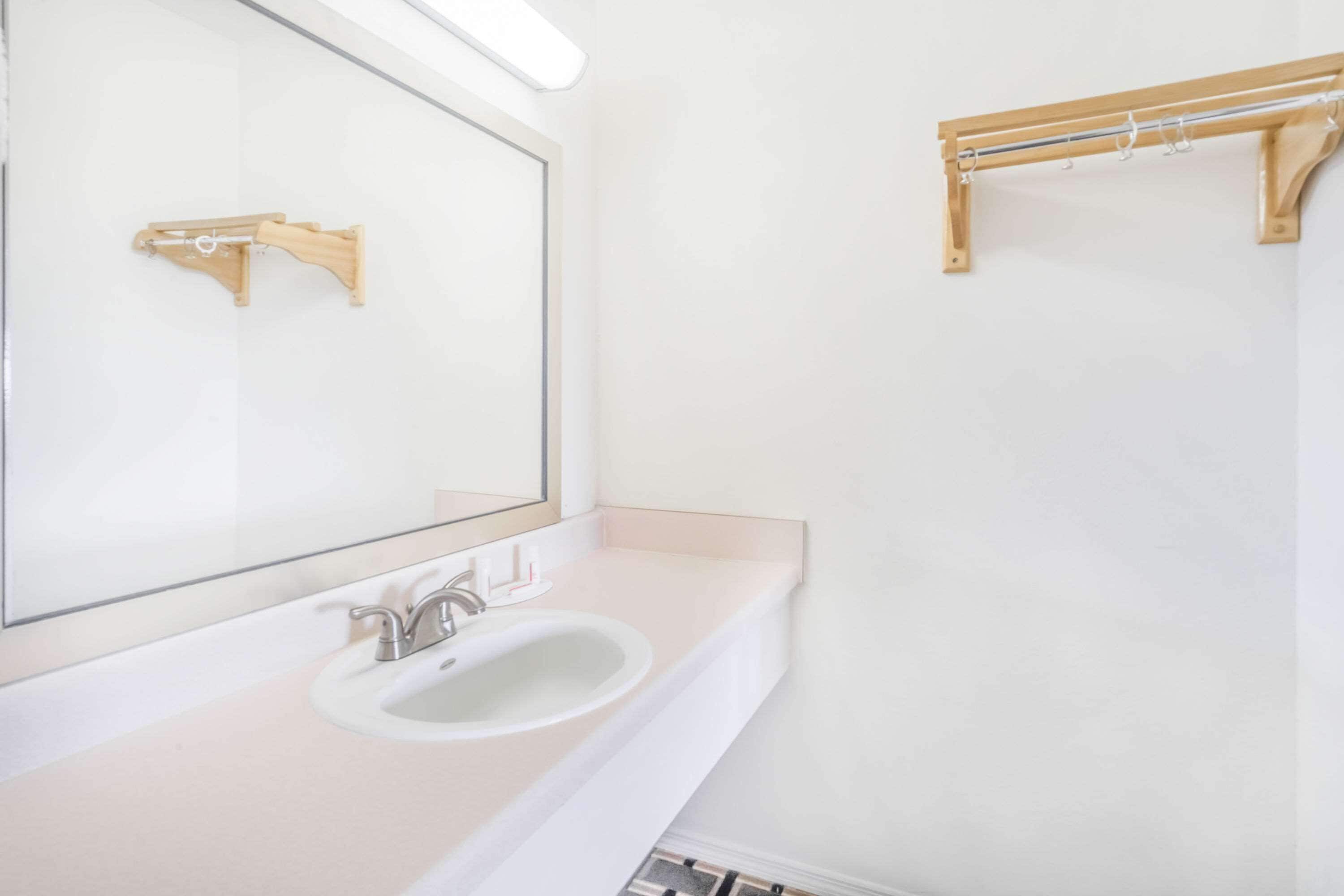 A bathroom with a sink, mirror, and wooden towel rack.