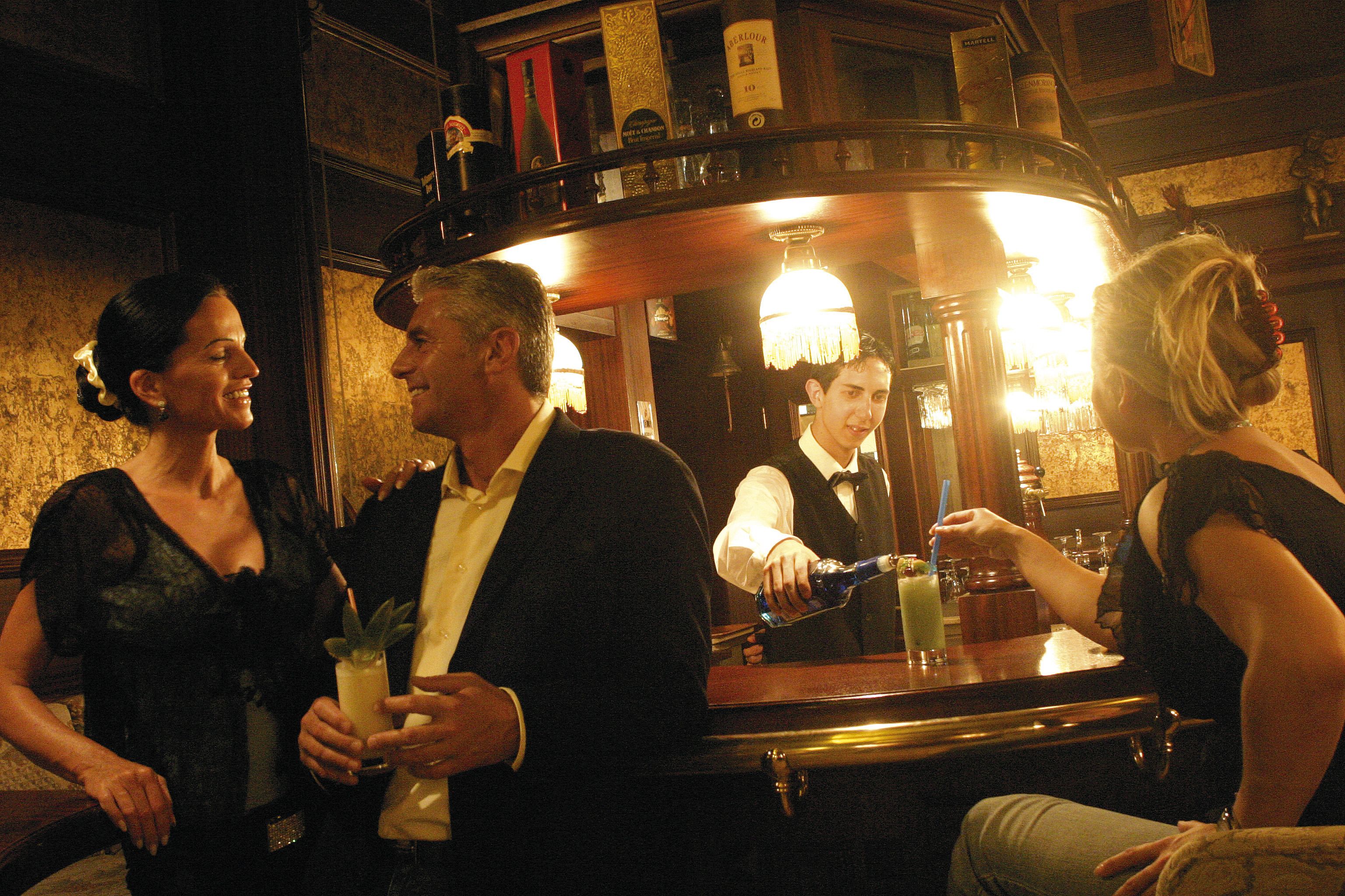 A bar area with a counter, bottles, and glasses.