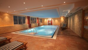 En indendørs swimmingpool med flisegulv, vipper og liggestole.