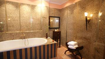 Un baño con una bañera independiente grande, un tocador con espejo y un perchero para toallas.