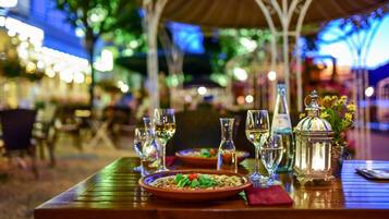 Un área de comedor al aire libre con mesas dispuestas para comidas, copas y un farol.