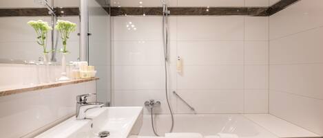 Un baño moderno con lavamanos, espejo y ducha.
