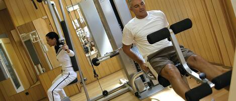 Un gimnasio con equipo de ejercicio, paredes de madera y un espejo.