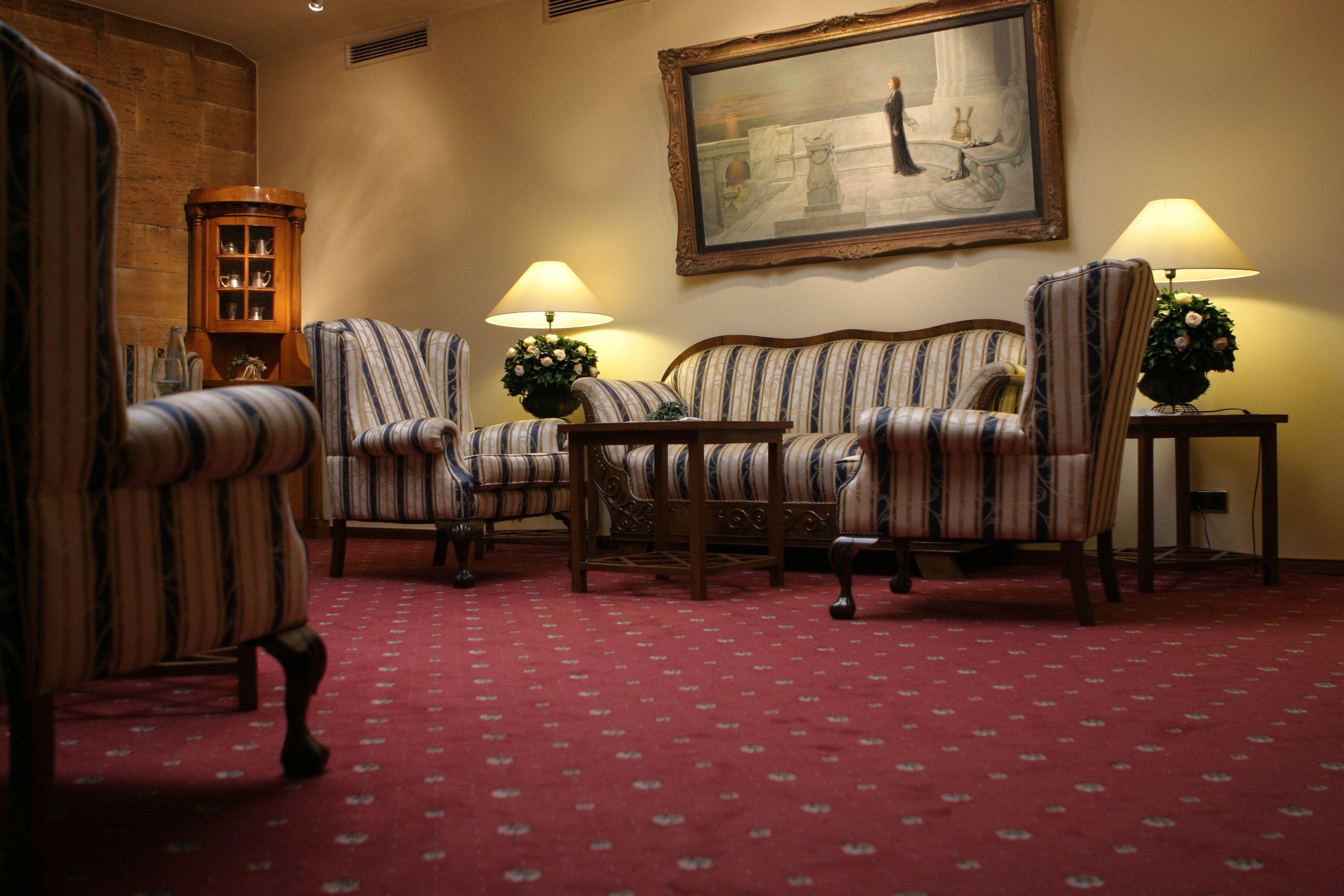 Une pièce avec des fauteuils à rayures, un canapé, un meuble en bois et un tableau au mur.