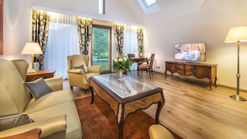 Un salon spacieux avec un plafond haut, un confortable ensemble de canapés, une table basse en bois et un téléviseur posé sur un meuble en bois.