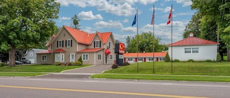 A two-story building with a red roof, a small annex with a red roof, and a flagpole with multiple flags.