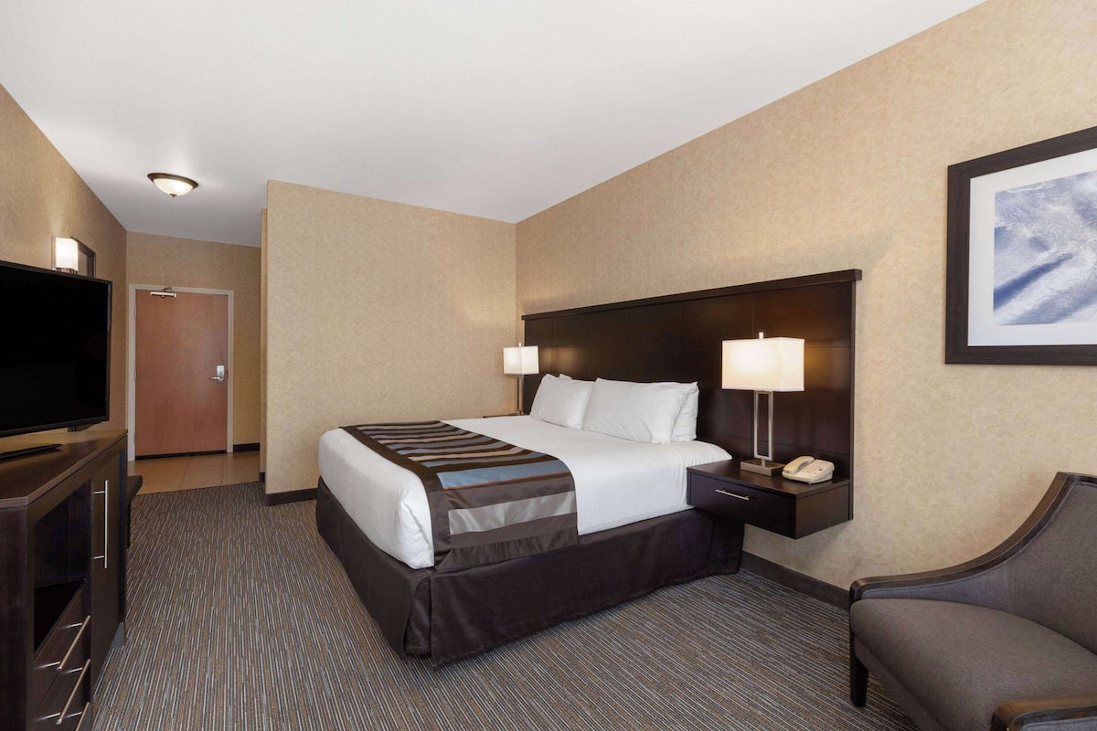A hotel room with a bed, bedside lamps, a TV, a desk, and a chair.