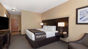 A hotel room with a bed, bedside lamps, a TV, a desk, and a chair.