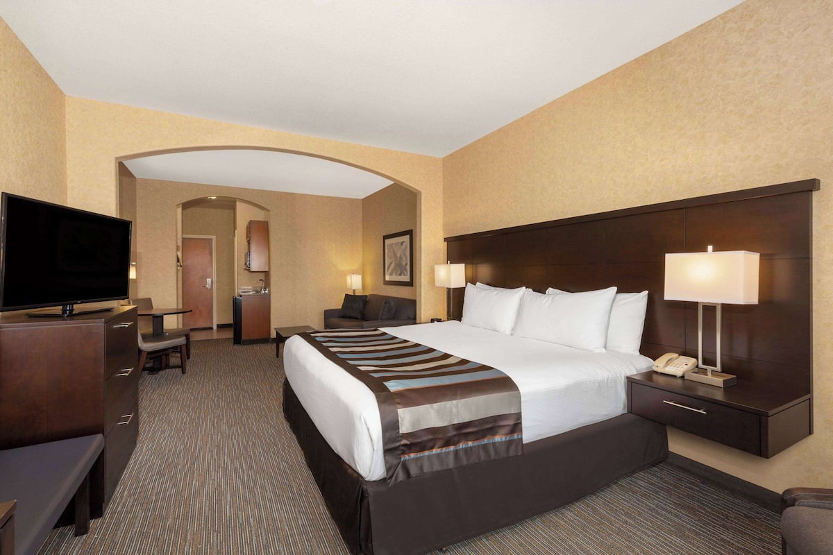 A hotel room with a large bed, a TV, a desk, and a chair.
