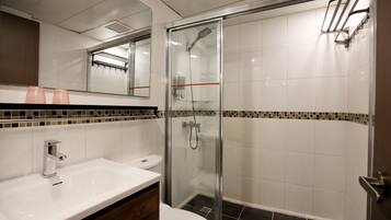 Un baño moderno con ducha de vidrio, un lavabo blanco y un espejo sobre el lavabo.