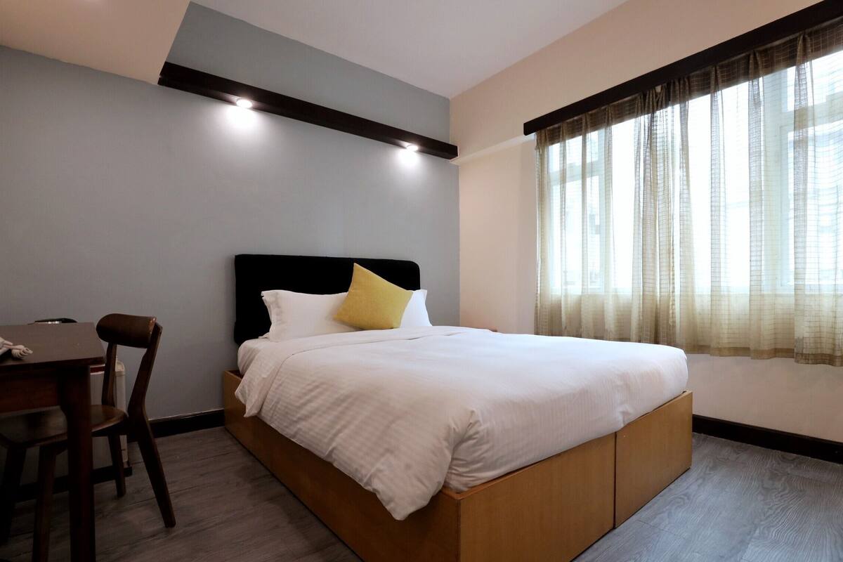 A hotel room with a bed, a desk, and a chair.