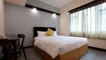 A hotel room with a bed, a desk, and a chair.