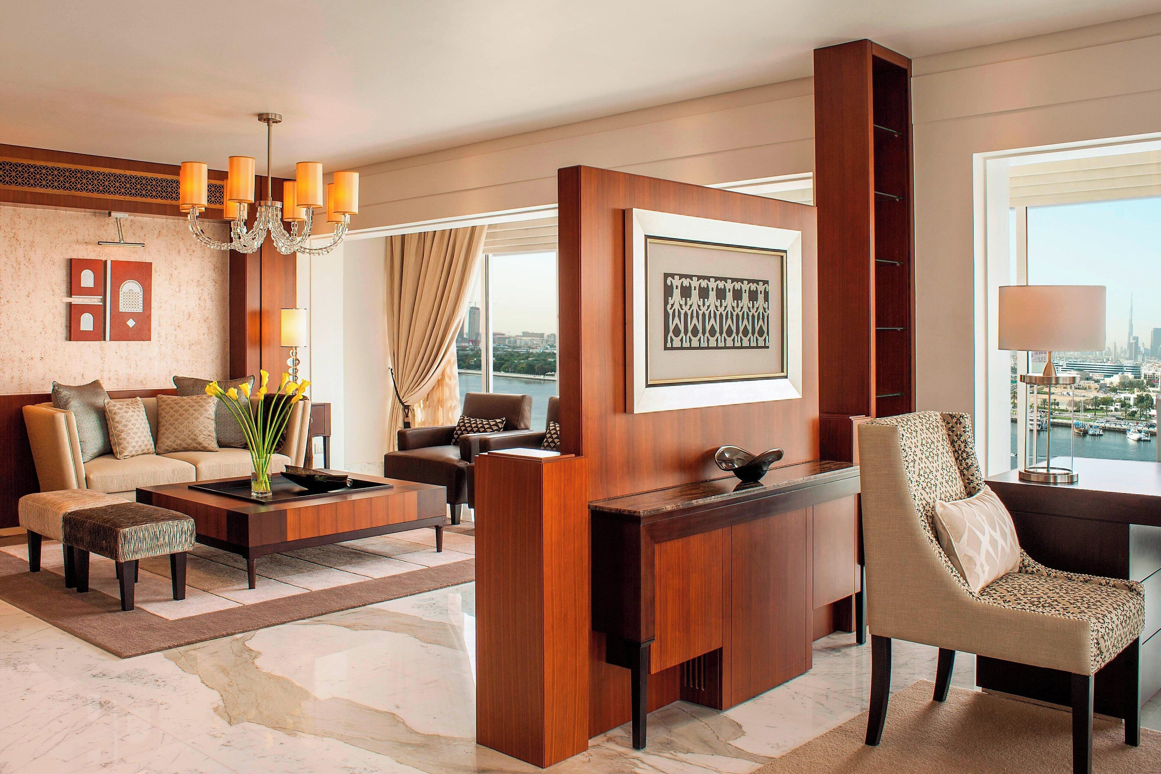 A modern hotel lobby with a sofa, armchairs, a coffee table, and a desk.