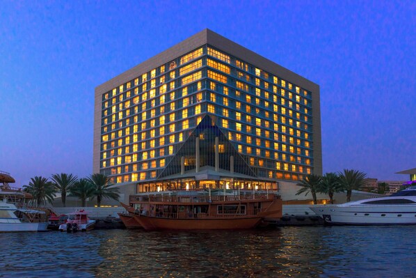 A modern hotel with a large glass facade, a rooftop pool, and a waterfront location. - Sheraton Dubai Creek Hotel & Towers (Dubai)