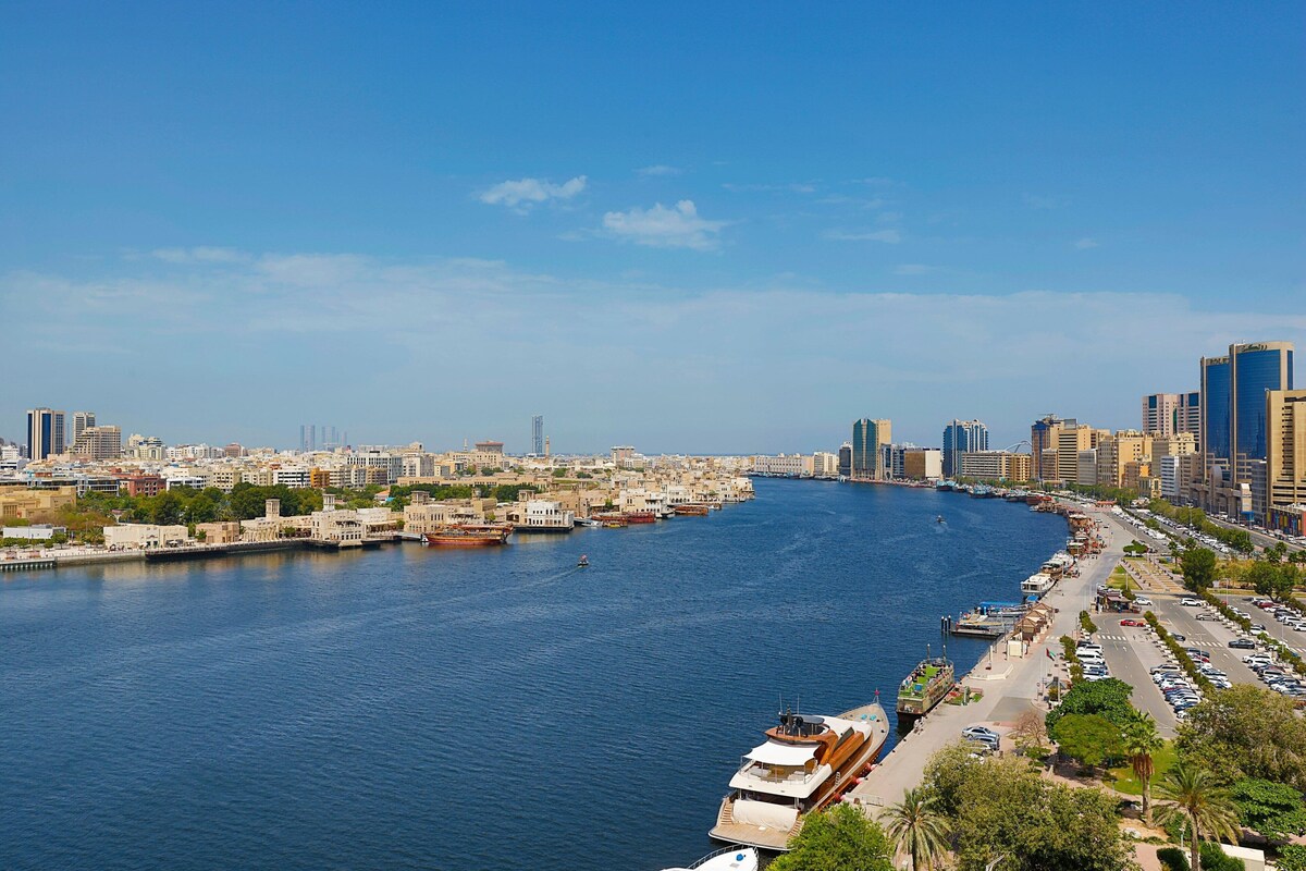A waterfront cityscape with a marina, buildings, and a clear sky.
