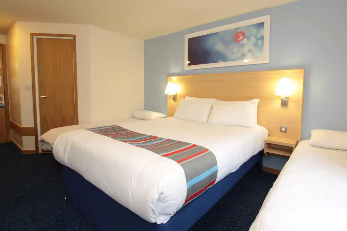 Une chambre d’hôtel avec un grand lit, deux tables de chevet, une tête de lit et un tableau au mur.
