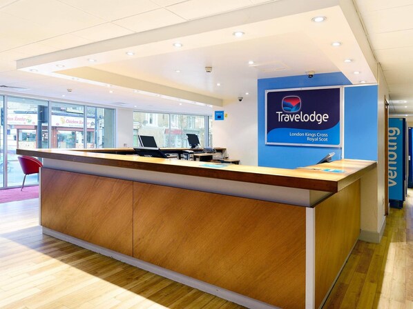 Mostrador de recepción de Travelodge con un cartel que indica su ubicación en London Kings Cross Royal Scot.