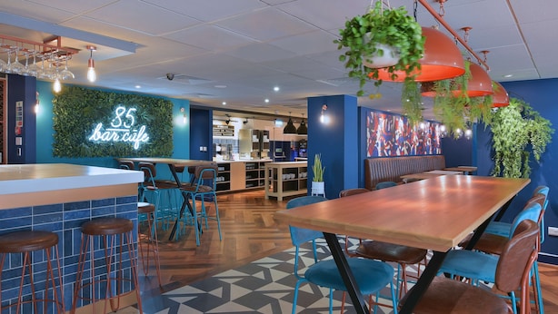 Ein modernes Café-Interieur mit Barbereich, Sitzgelegenheiten und einer Neonreklame.