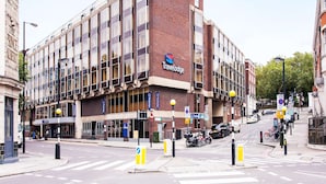 Ein Travelodge Hotel mit Ziegelrückseite, großen Fenstern und einem Schild, das eine beschränkte Parkzone kennzeichnet.
