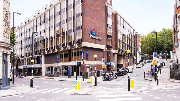 Ein Travelodge Hotel mit Ziegelrückseite, großen Fenstern und einem Schild, das eine beschränkte Parkzone kennzeichnet.