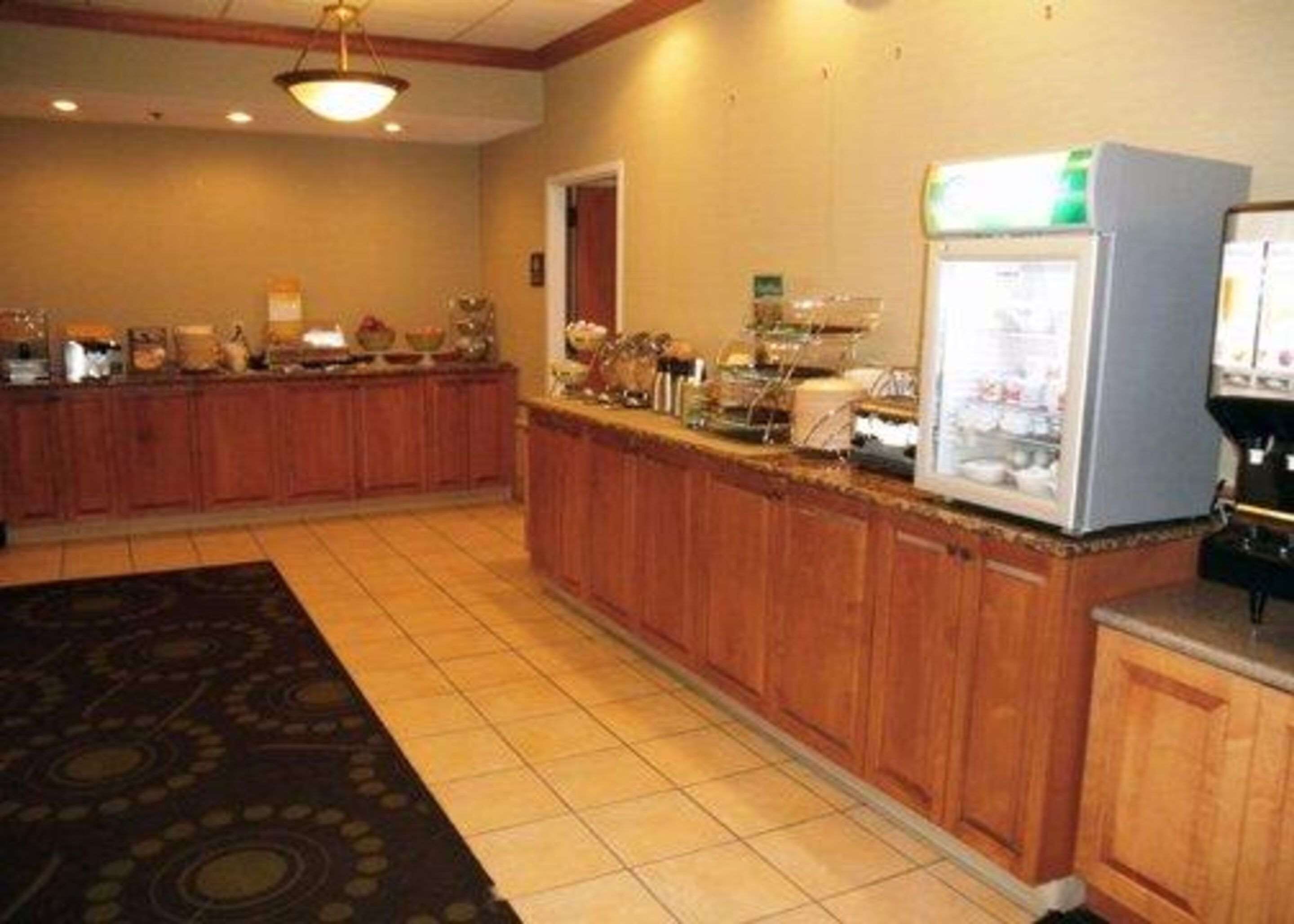 Una cucina d'albergo con armadietti in legno, un banco buffet e un frigorifero.