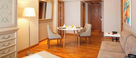 A modern living room with a round dining table, two chairs, a sofa, a lamp, and a cabinet.