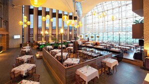 Un restaurante espacioso con techos altos, ventanas amplias y varias zonas de comedor.