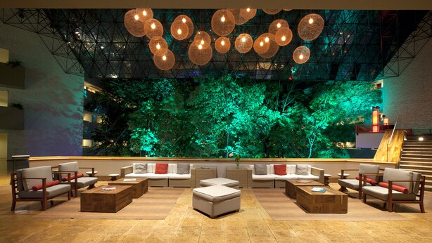 Un espacio lounge moderno con sofás, otomanas y mesas de centro de madera.